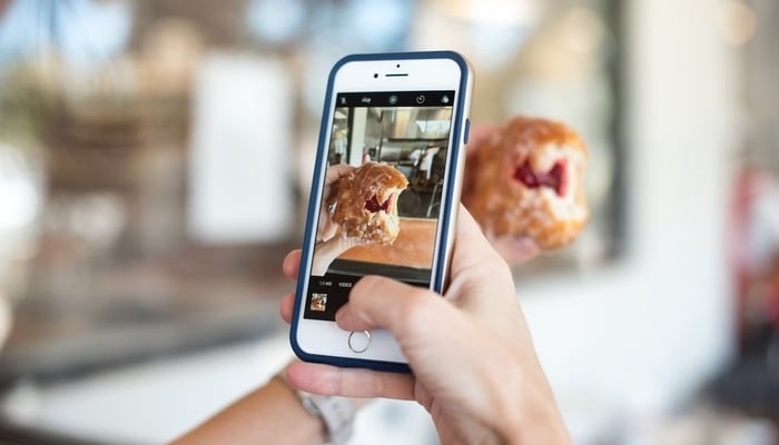 Social media in Guatemala / A person taking a photo of a jam-filled donut with an iPhone